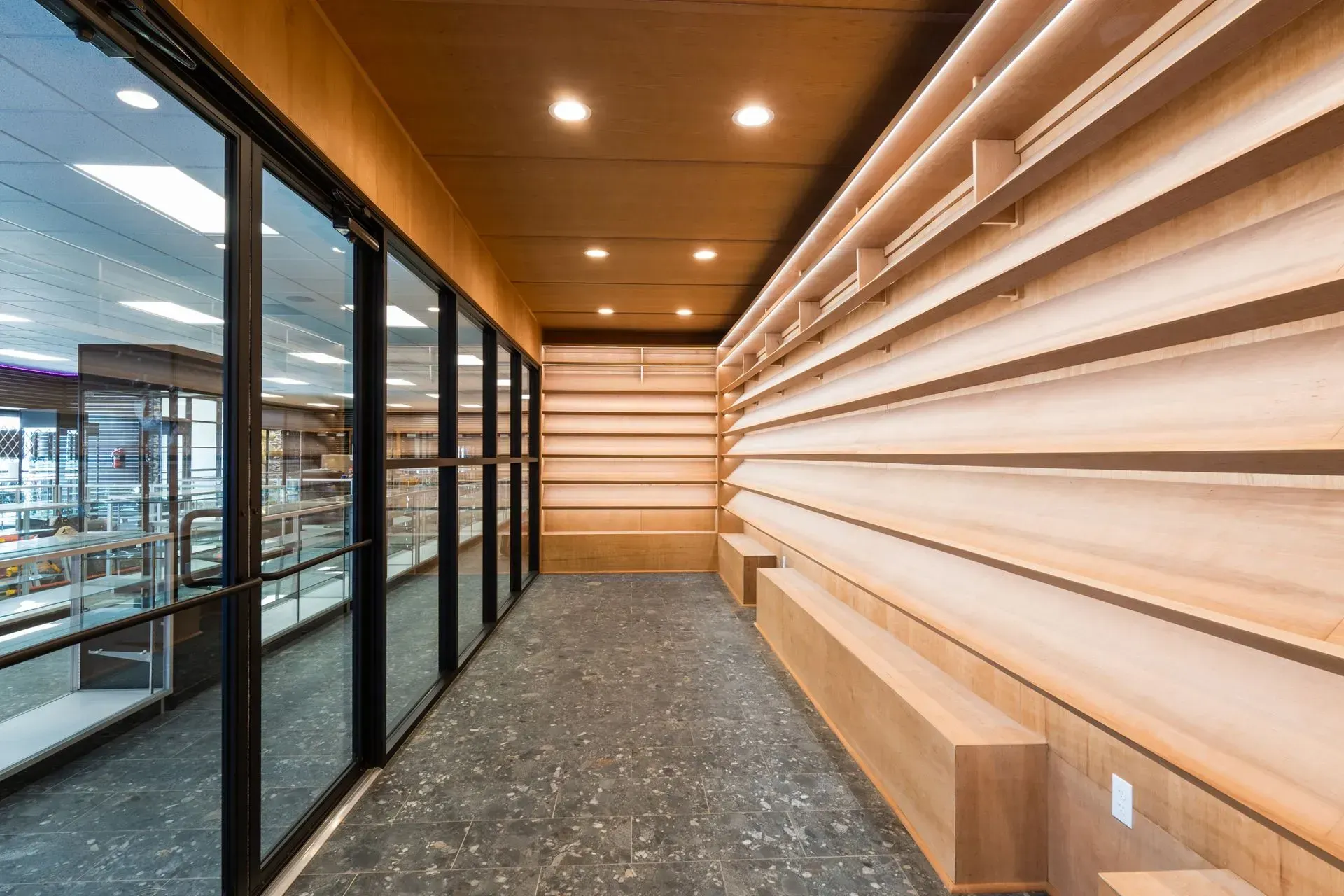 A long hallway with wooden shelves and a glass door.