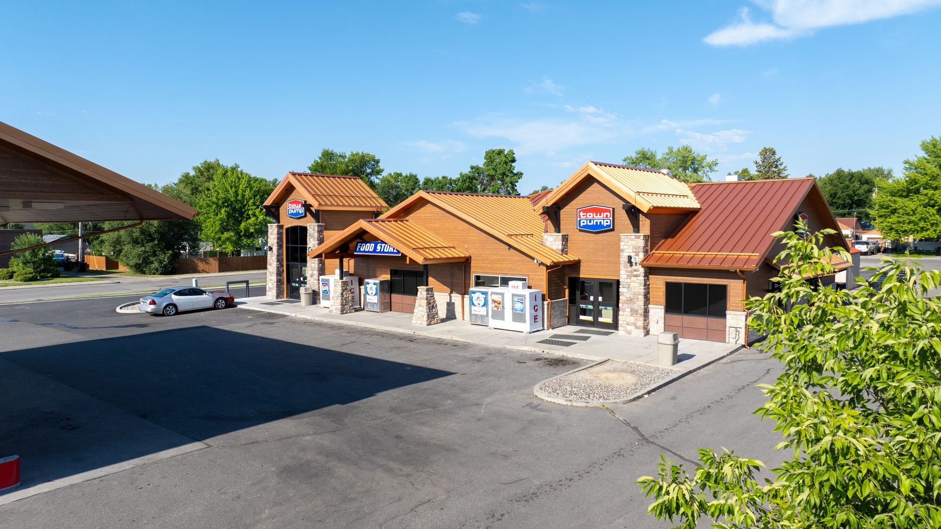 A large building with a red roof is surrounded by trees and a parking lot.