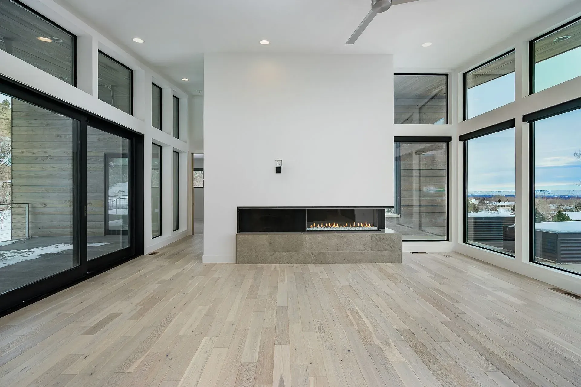 An empty living room with a fireplace and lots of windows.