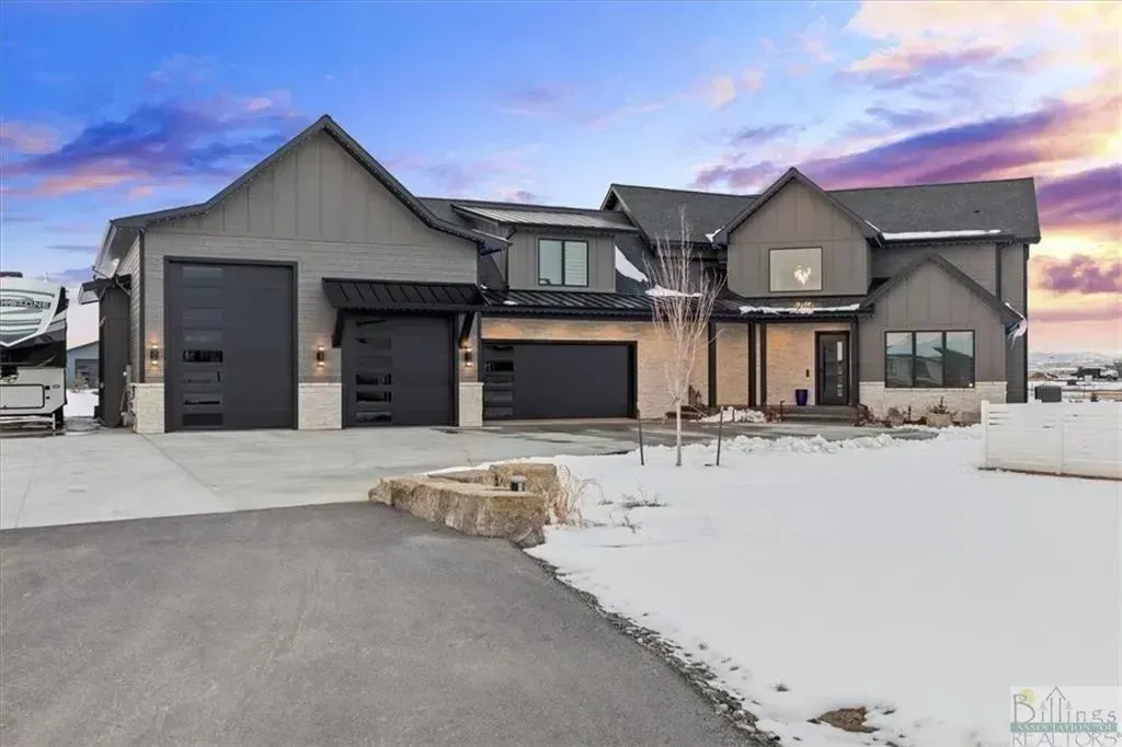 A large house with two garages is for sale in the snow.