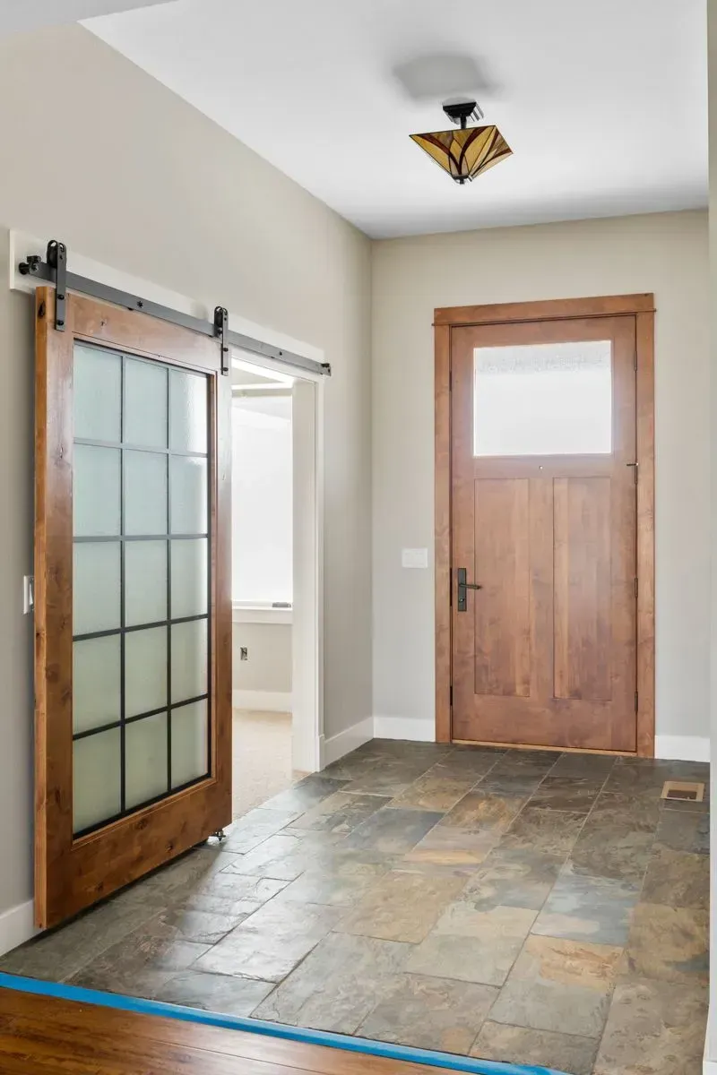 A hallway with a sliding barn door and a wooden door.