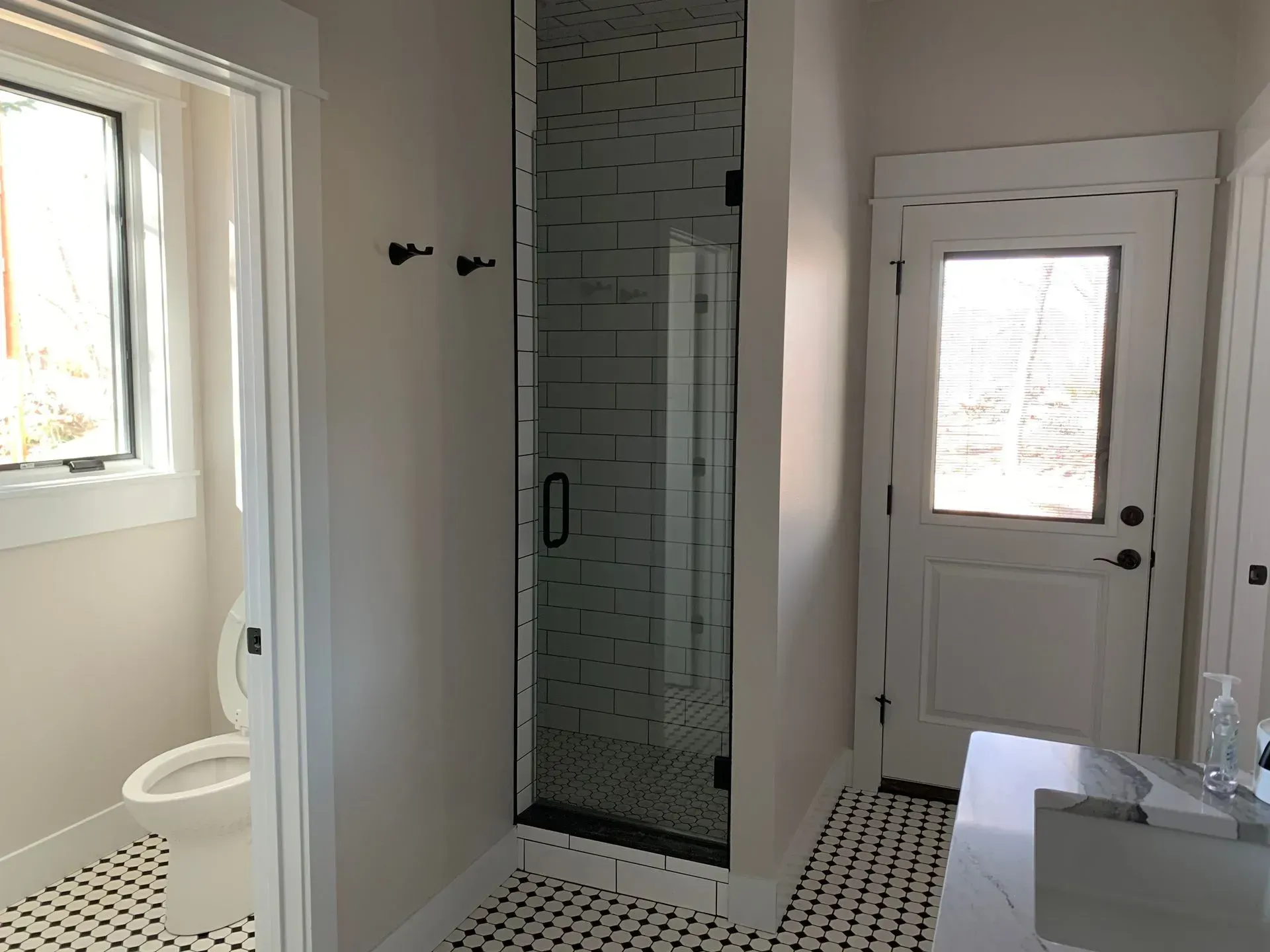 A bathroom with a walk in shower , toilet , sink and window.