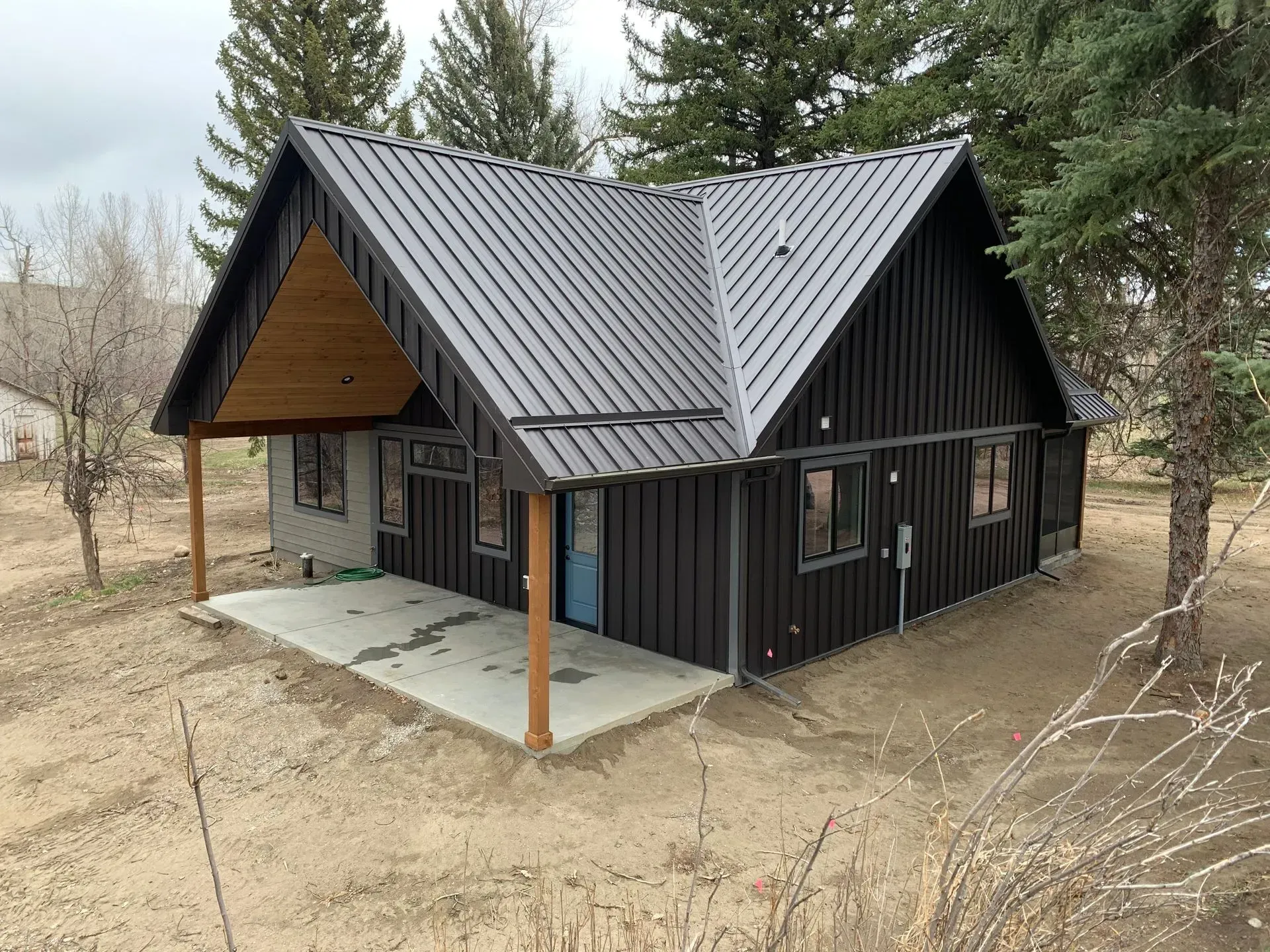 A small black house with a metal roof and a porch.