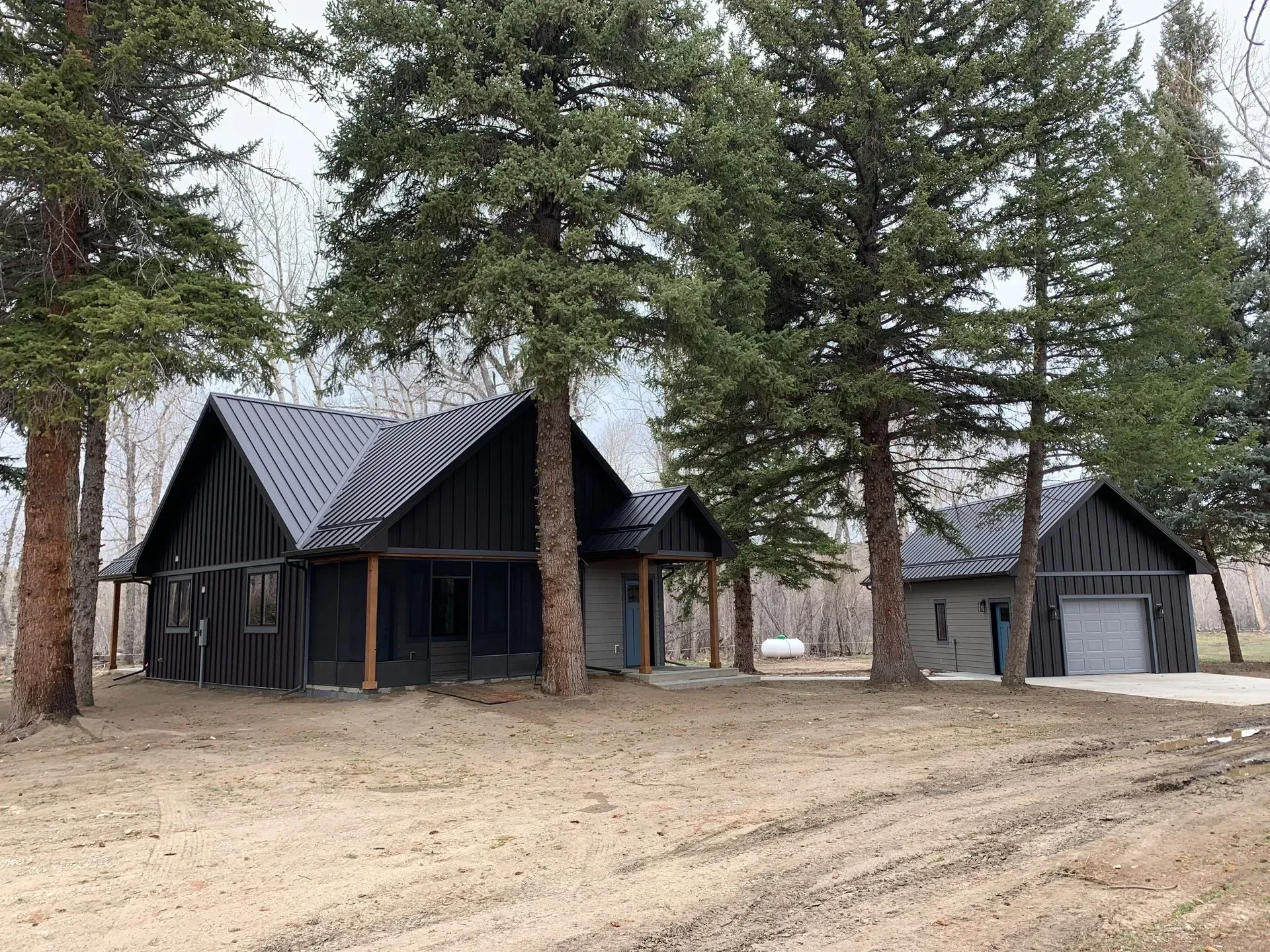 A couple of houses sitting next to each other in a field surrounded by trees.