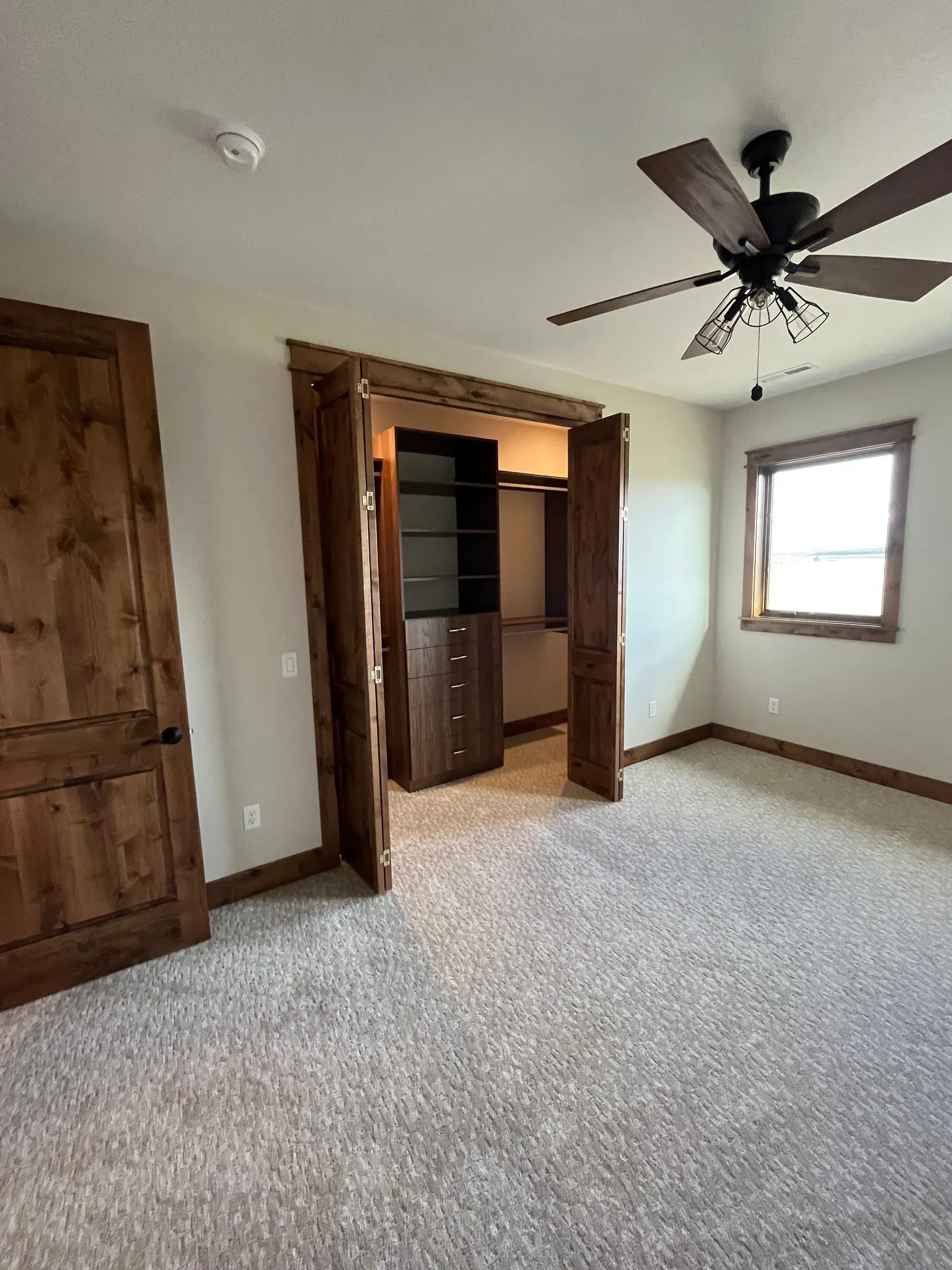 A bedroom with a ceiling fan and a walk in closet.