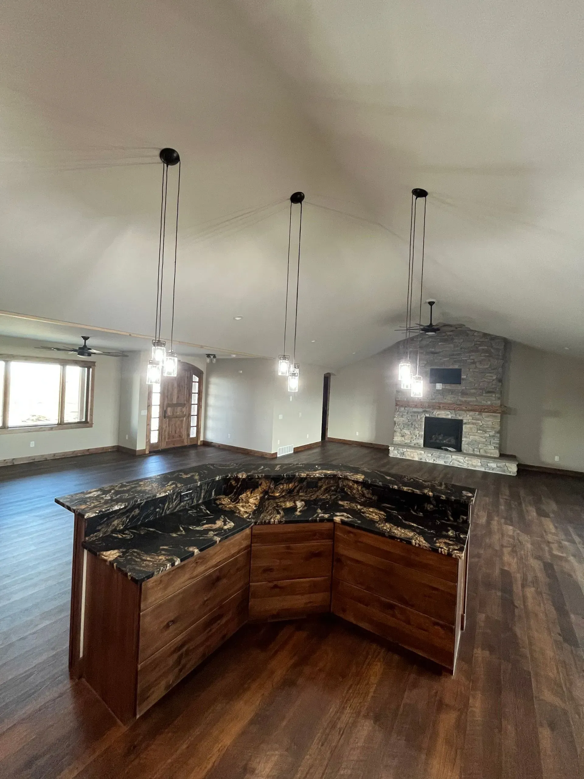 A large empty room with a kitchen island and a fireplace.