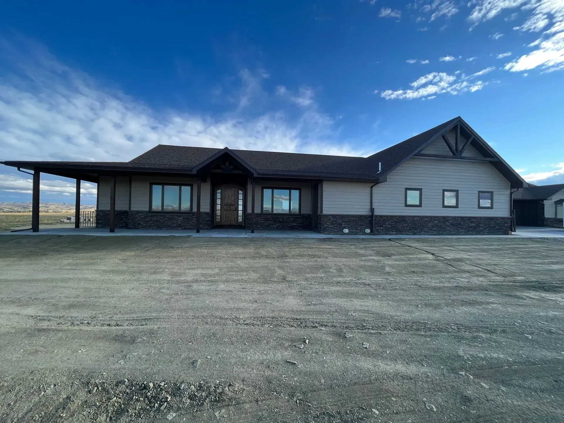 A large house with a lot of windows is sitting on top of a dirt field.