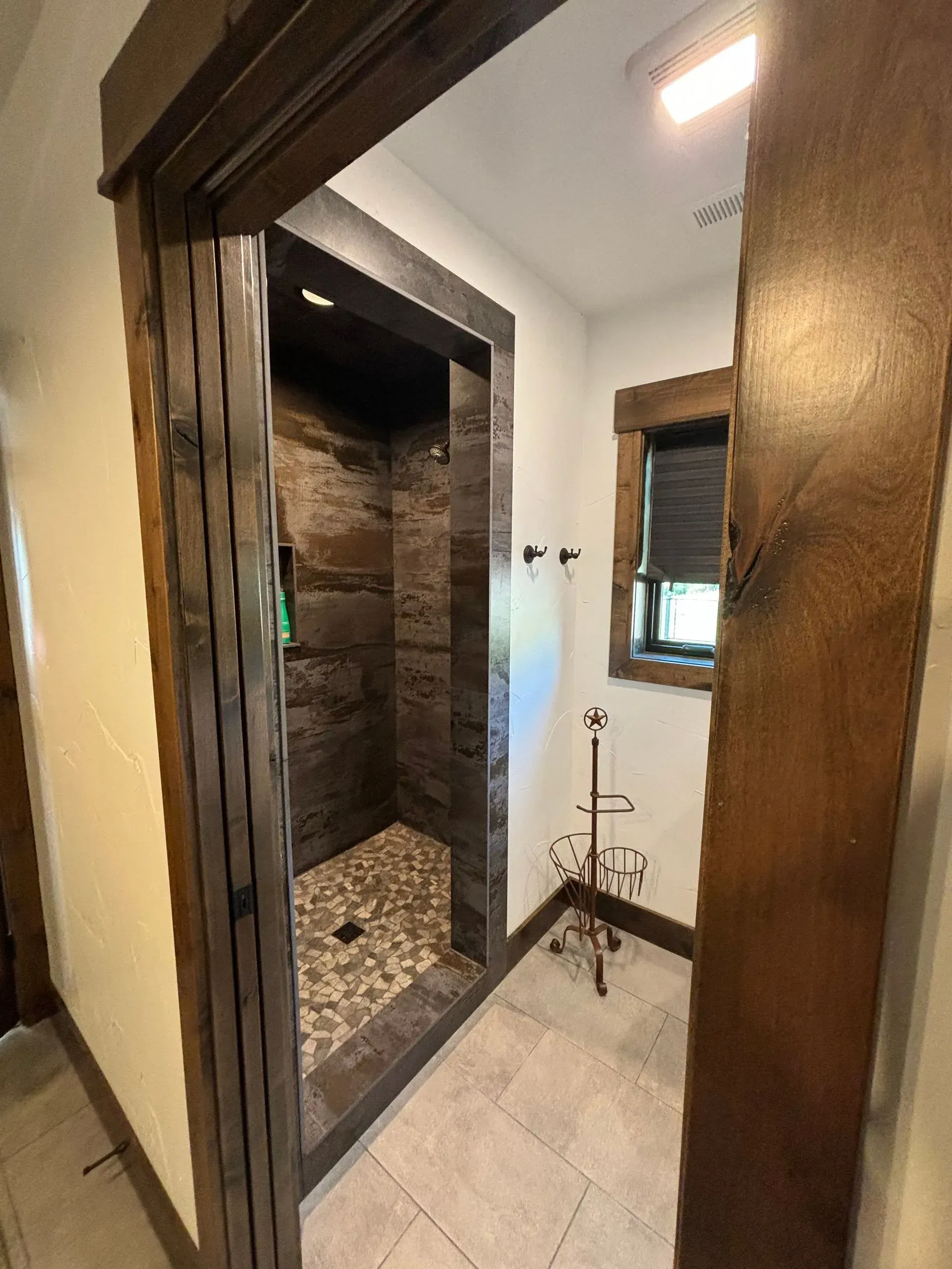 A bathroom with a walk in shower and a window.