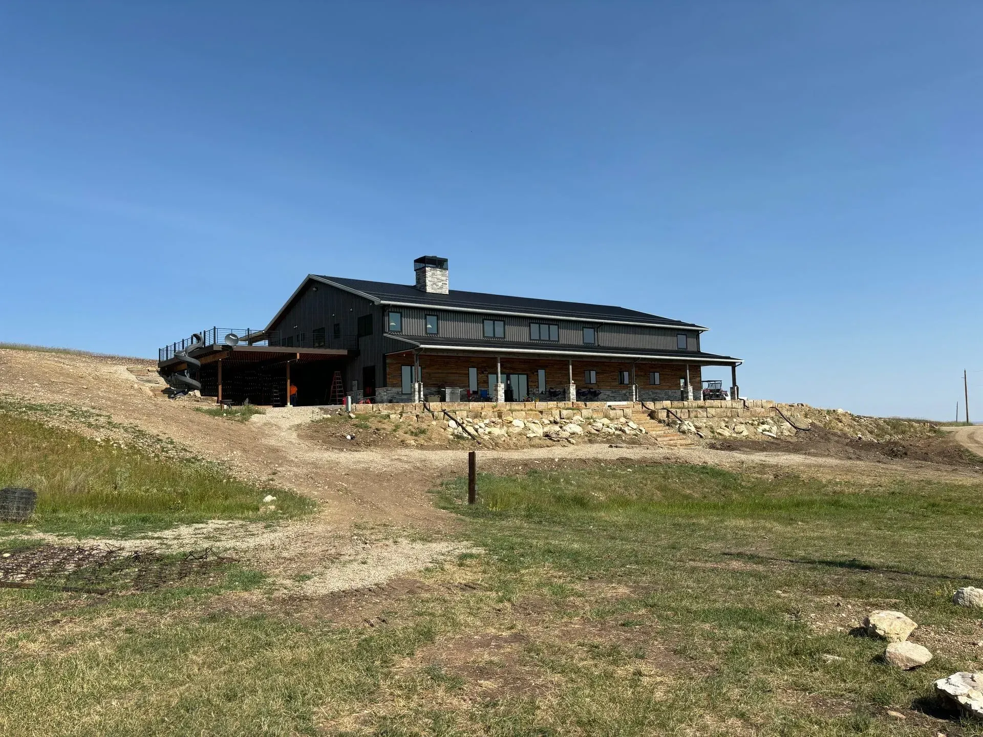 A large house is sitting on top of a grassy hill.