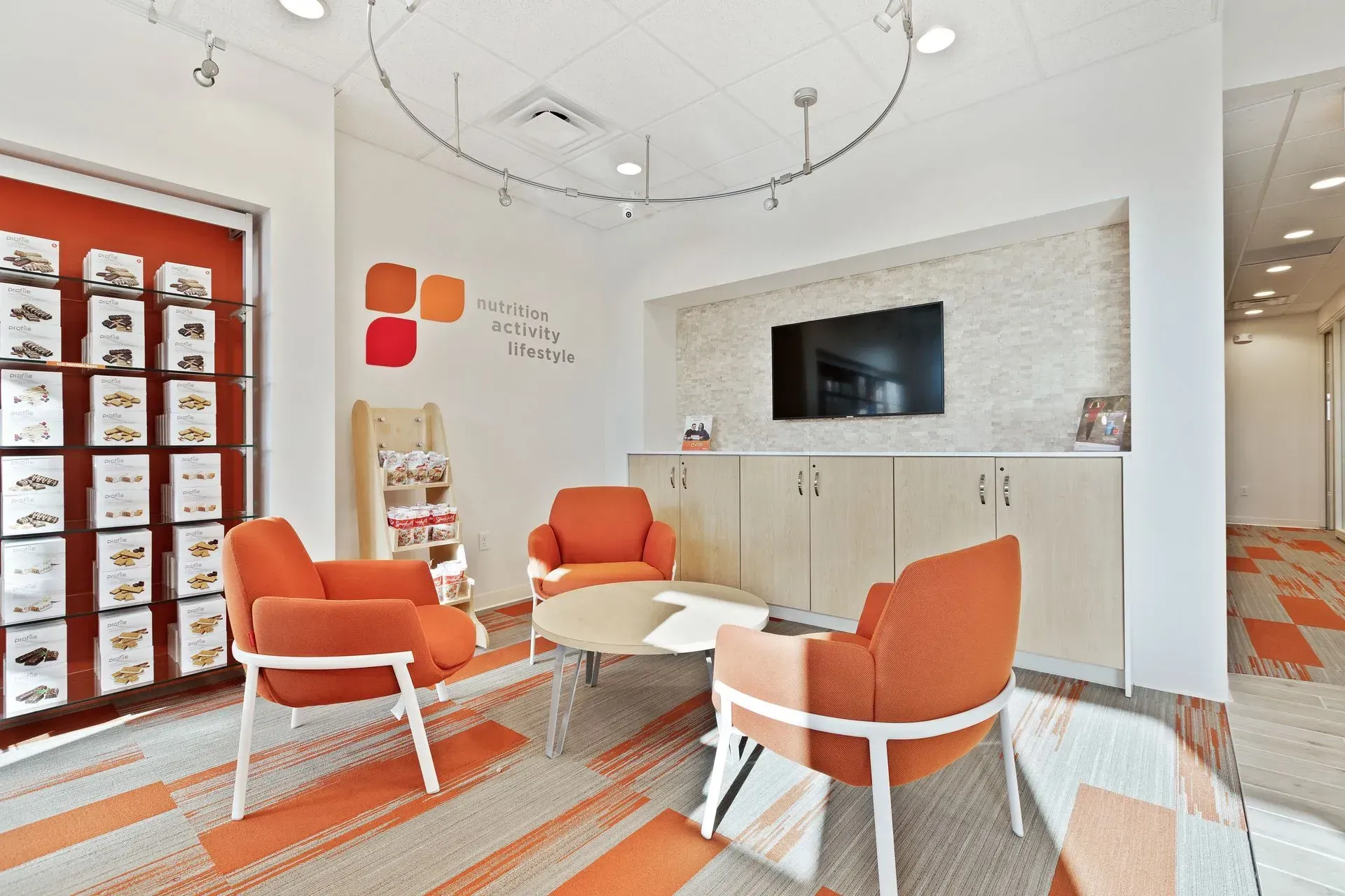 A living room with orange chairs , a table , and a television.