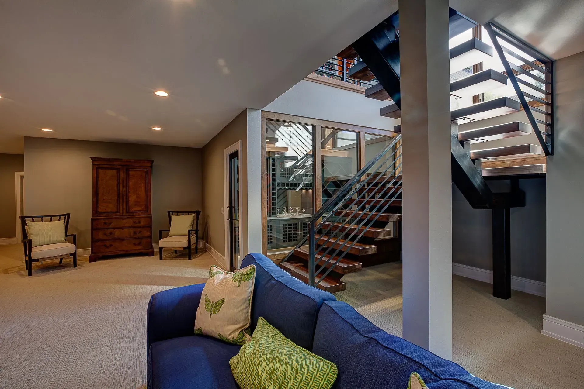 A living room with a blue couch and stairs in the background.