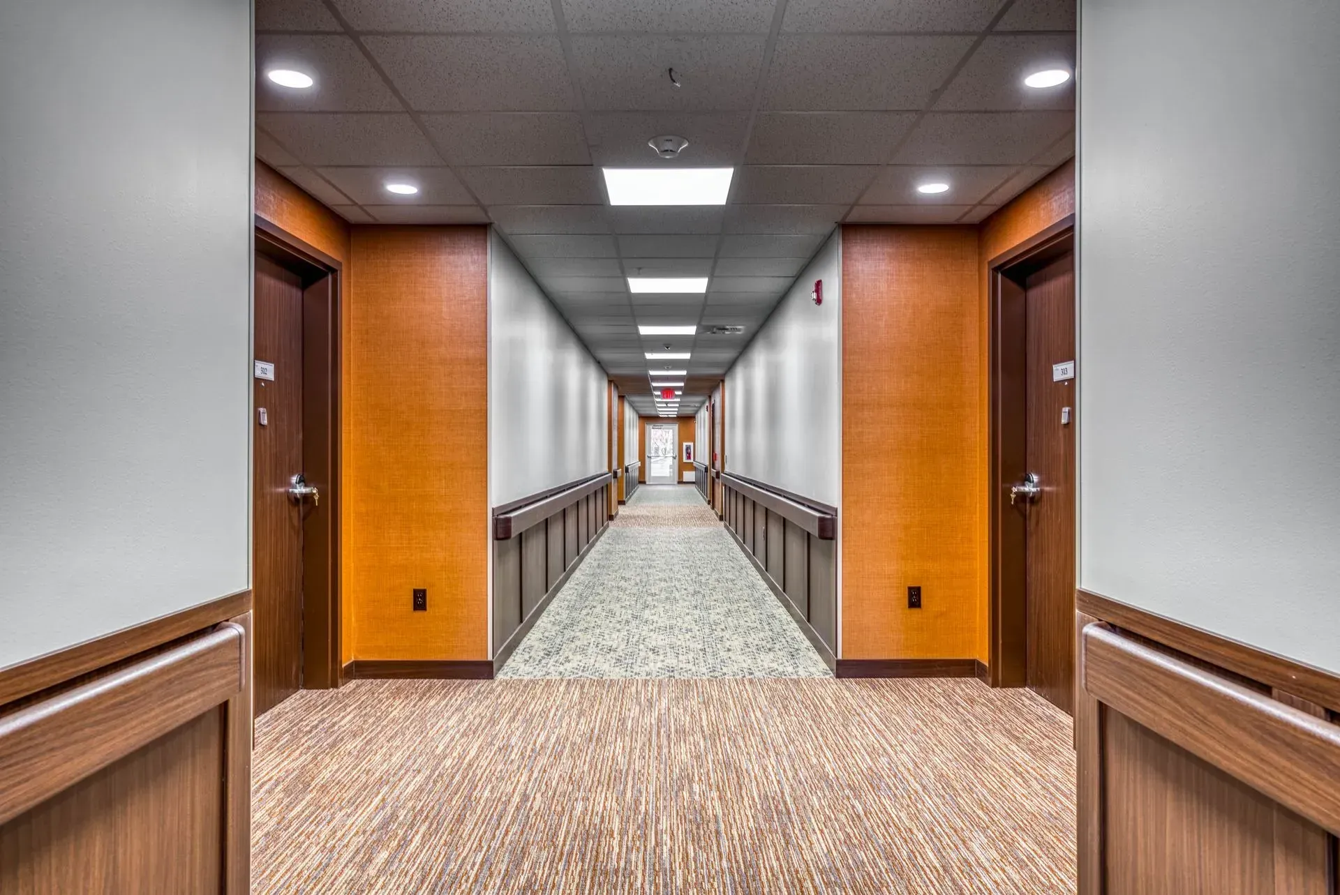A long hallway with wooden walls and doors in a building.