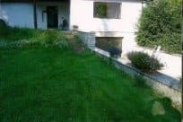 Ein großer, üppiger grüner Rasen vor einem weißen Haus.