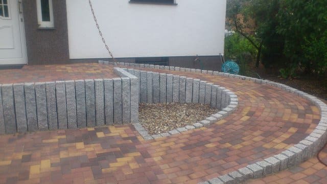 Vor einem Haus wird ein gemauerter Gehweg gebaut.