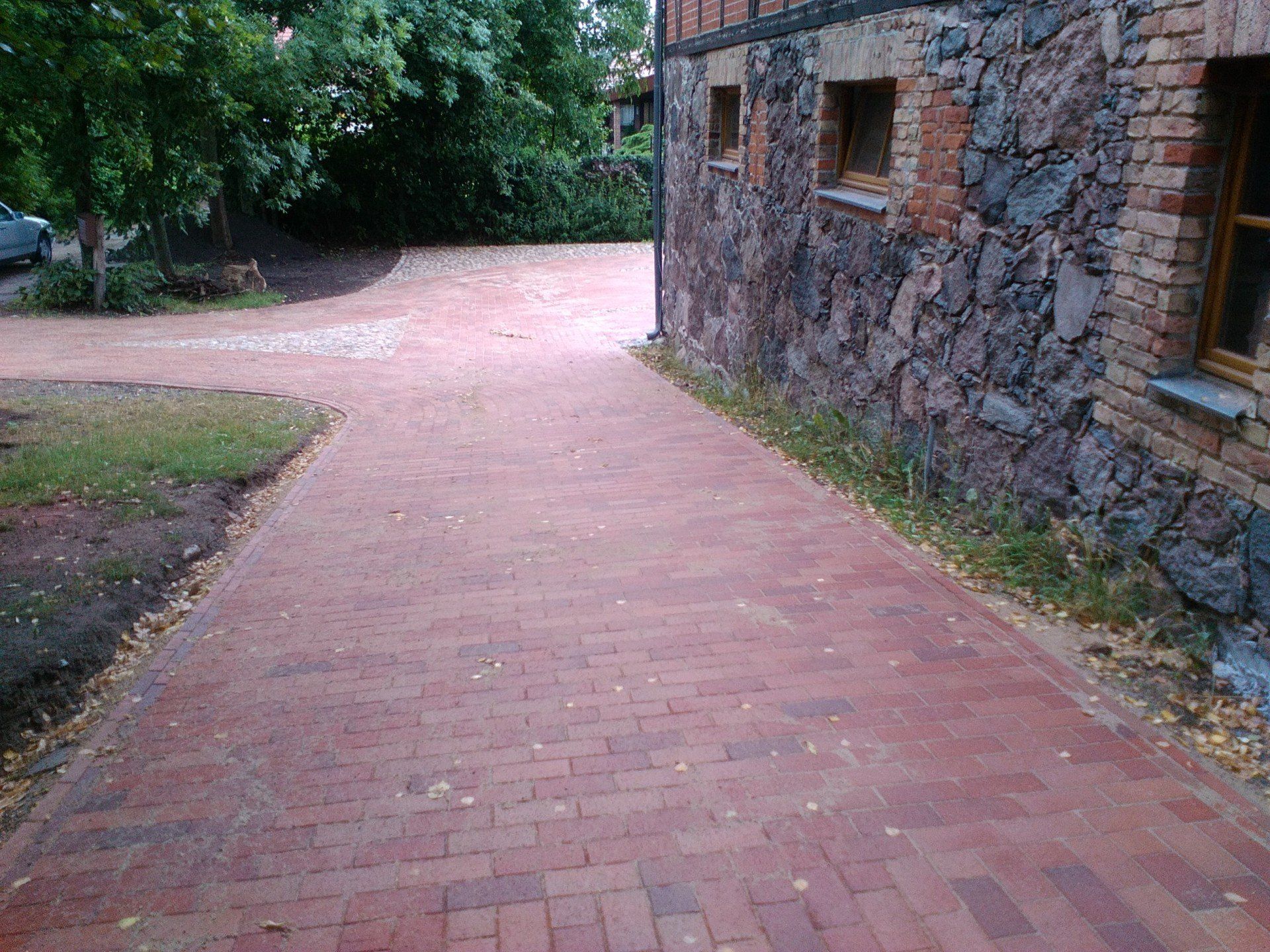Ein roter Backsteinweg führt zu einem Steingebäude.