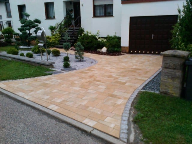 Eine Auffahrt, die zu einem weißen Haus mit einem braunen Garagentor führt