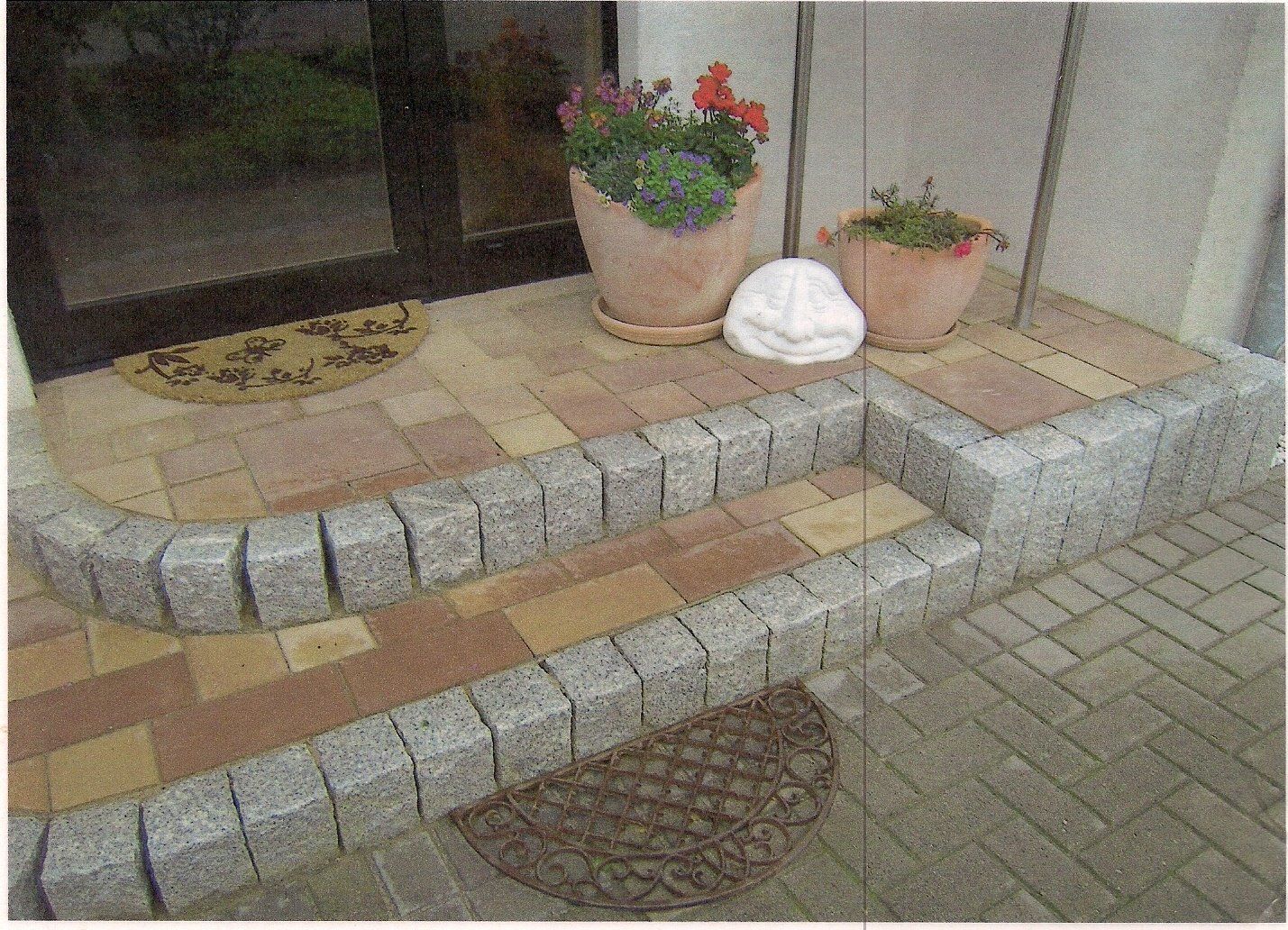 Eine gemauerte Veranda mit Fußmatte und Topfpflanzen