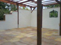 Eine Terrasse mit Pergola und einem Spiegel an der Wand.