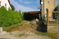 Vor einem Haus liegt ein großer Erdhaufen.