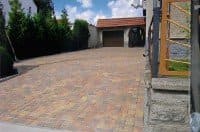 Eine gepflasterte Auffahrt, die zu einer Garage und einem Haus führt.