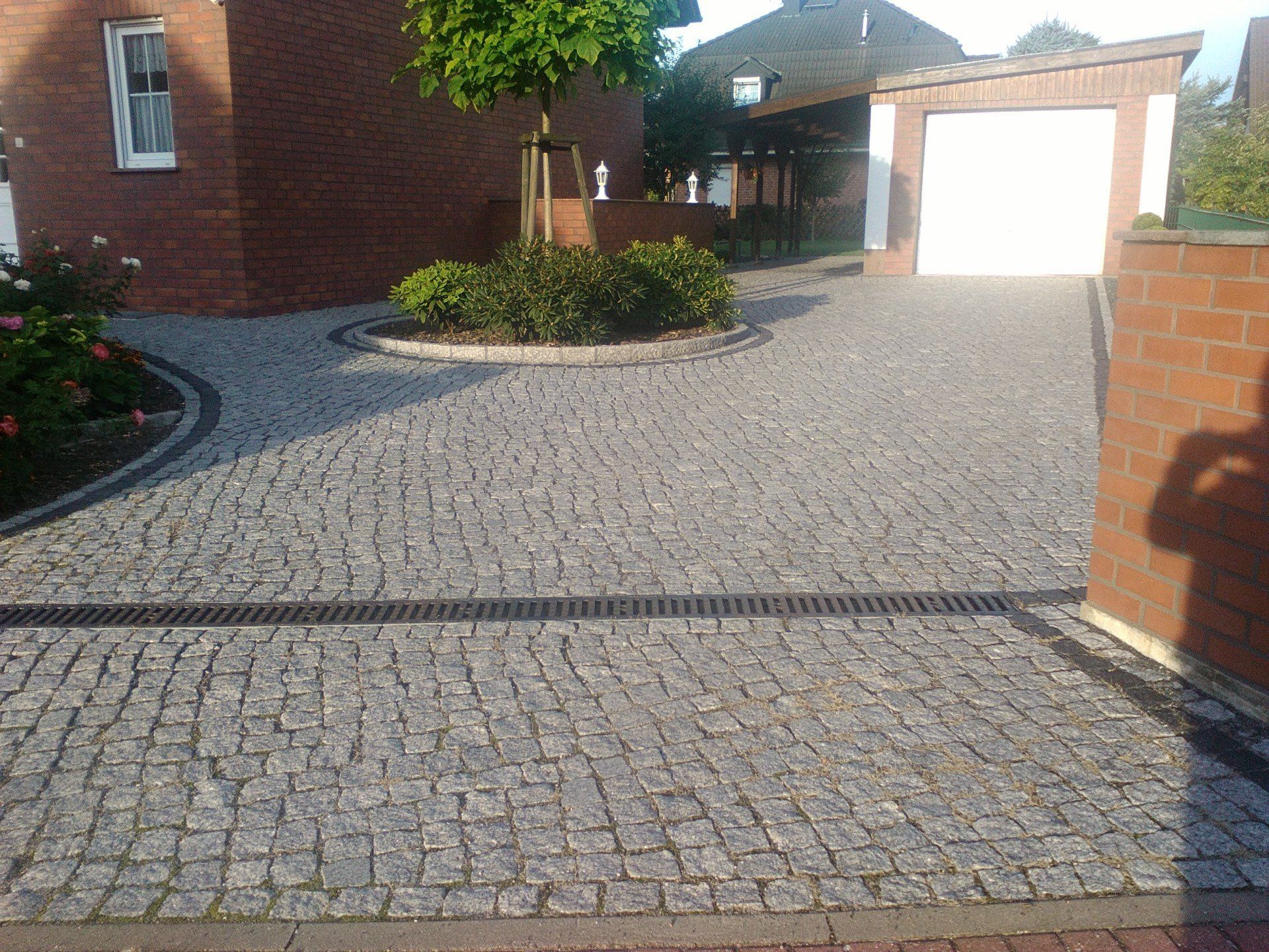 Eine gepflasterte Auffahrt, die zu einem Backsteinhaus führt