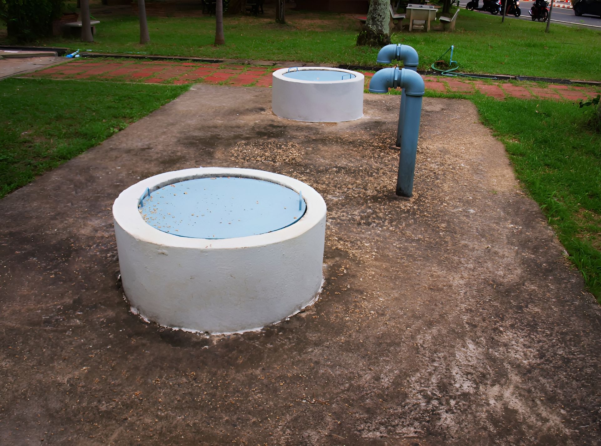 Two Concrete Water Tanks and a Blue Pipe in a Park — Paap's Cleansing Services in Woodgate, QLD