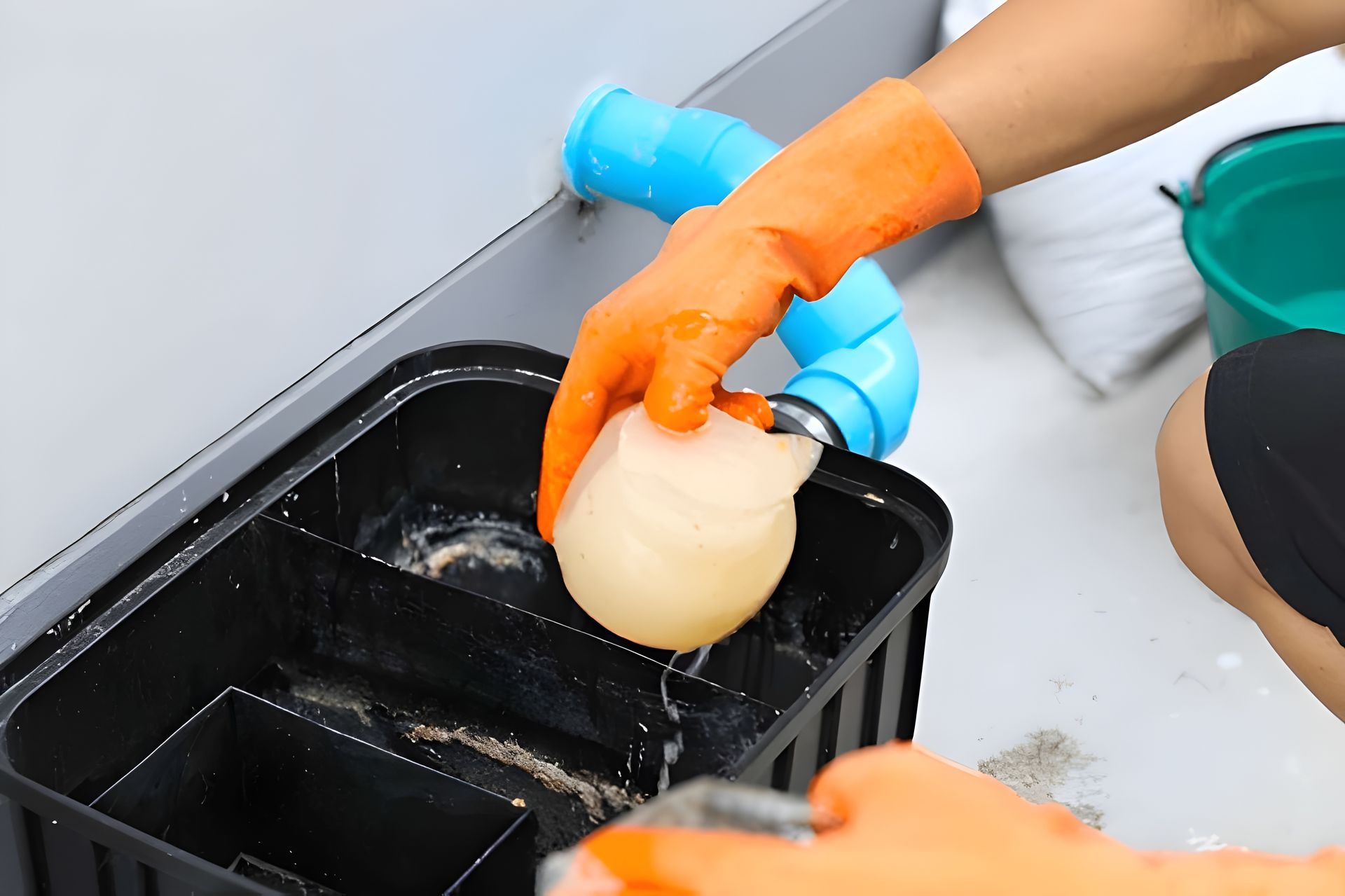 Person Wearing Orange Gloves Cleaning a Grease Trap — Paap's Cleansing Services in Mount Perry, QLD