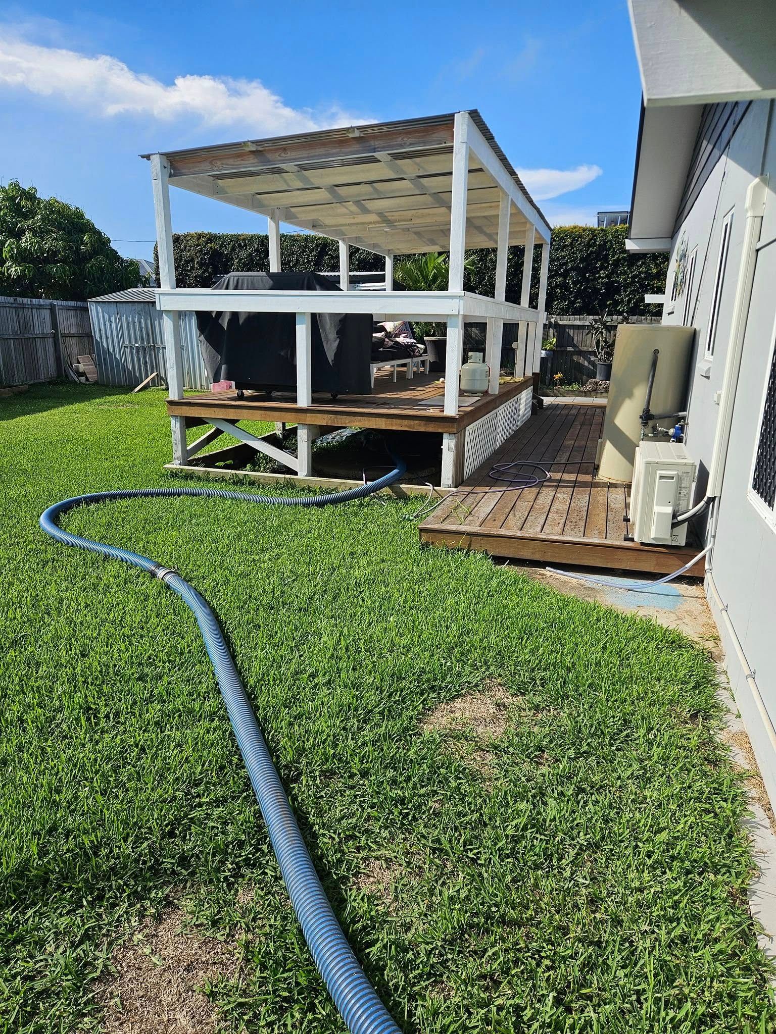 Backyard With a Wooden Deck, Pergola, and a Hose — Paap's Cleansing Services in Bargara, QLD