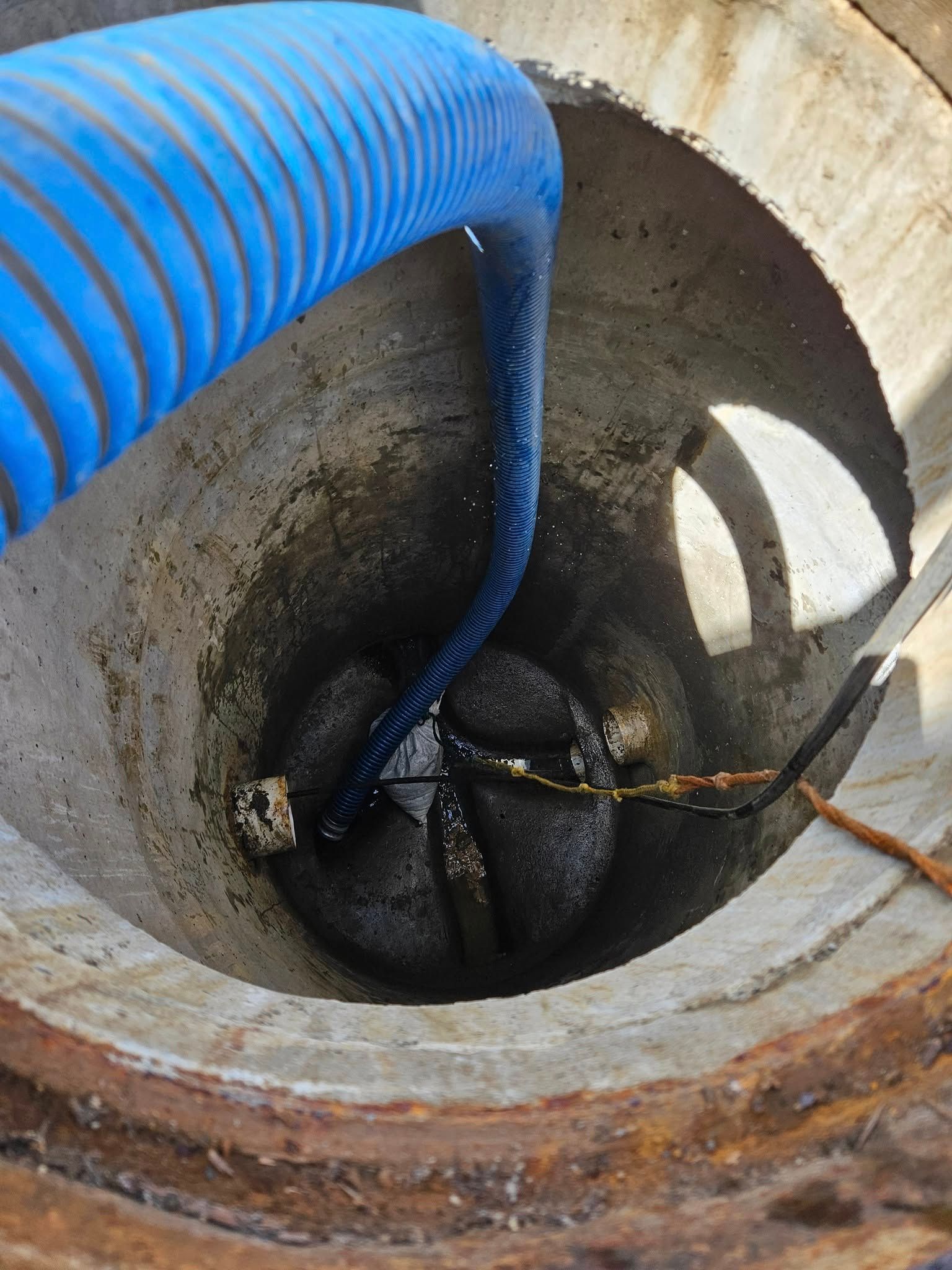 Blue Hose Descending Into a Concrete Manhole — Paap's Cleansing Services in Branyan, QLD