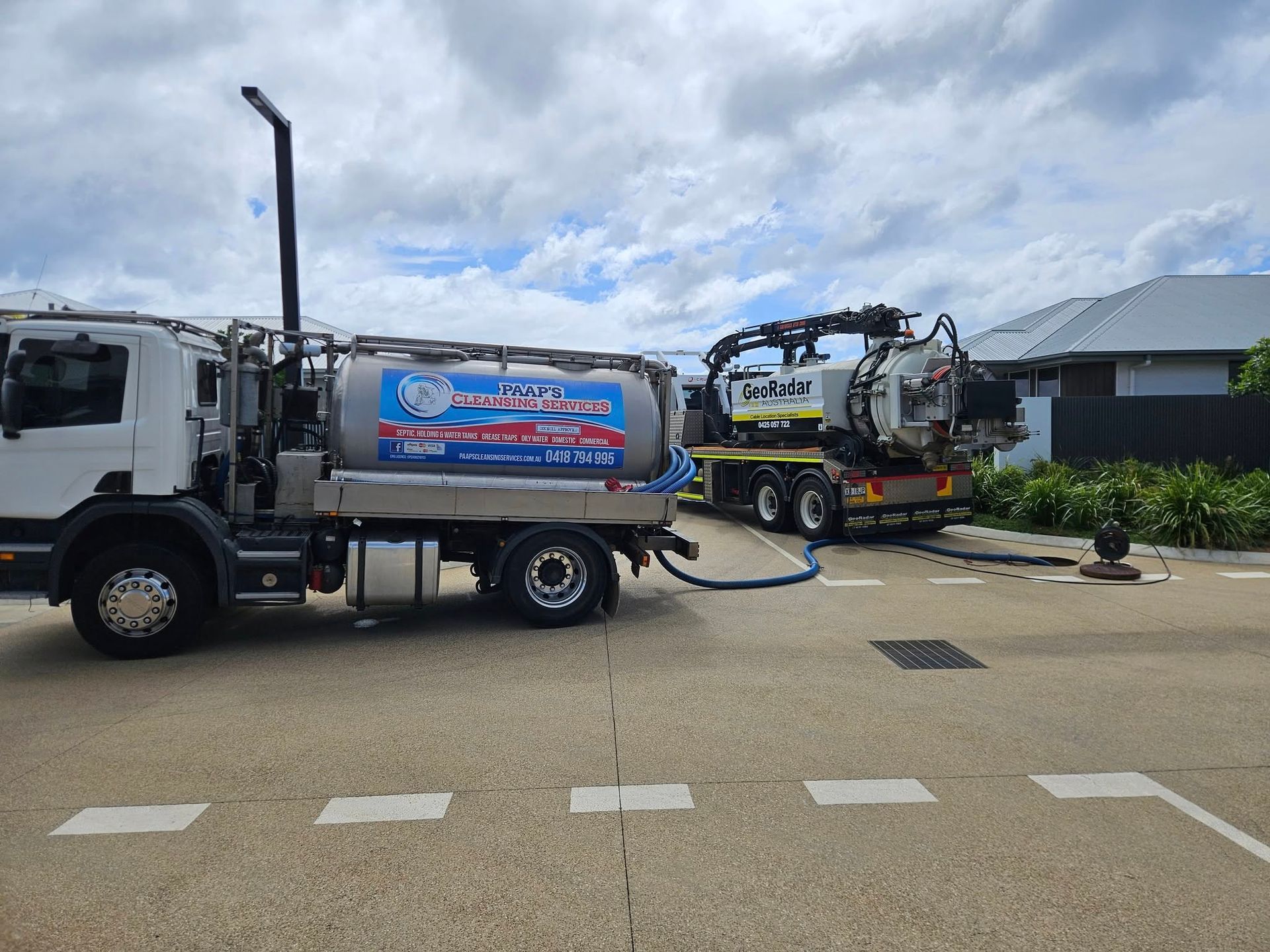Two Trucks Vacuuming a Drain on a Street — Paap's Cleansing Services in Lowmead, QLD