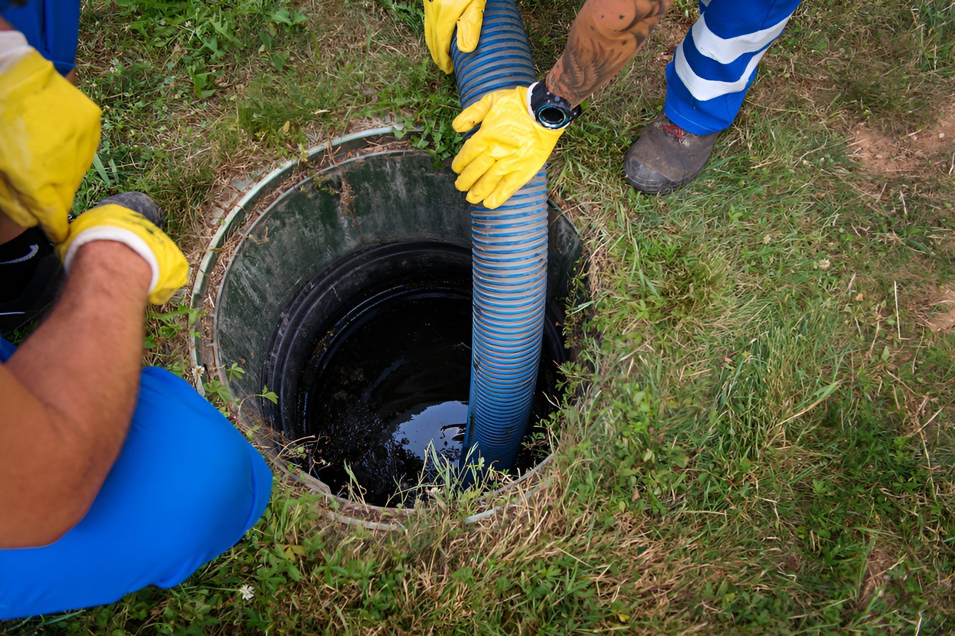 Two People in Yellow Gloves Working on an Open Septic Tank in a Grassy Area — Paap's Cleansing Services in Gin Gin, QLD