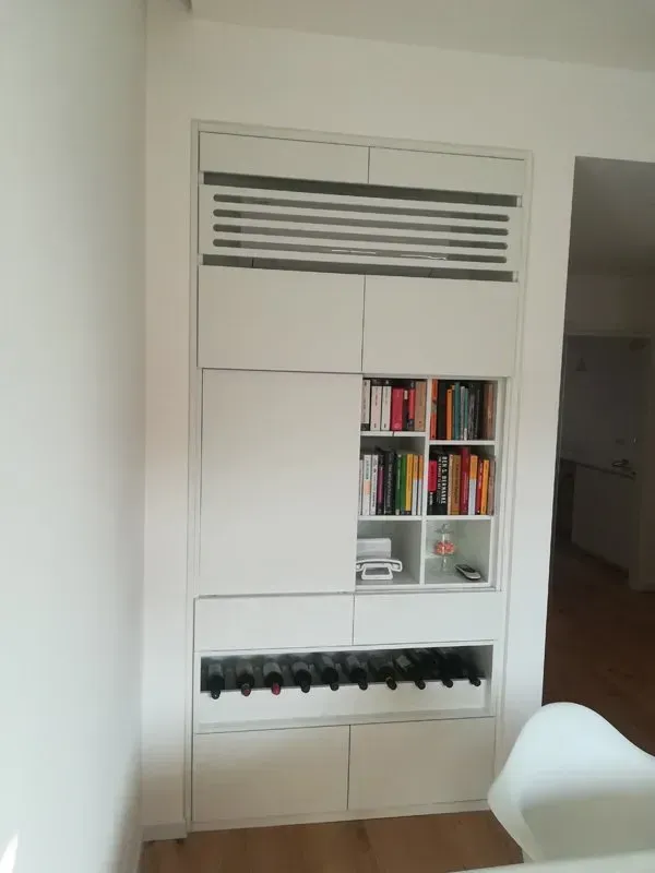 Una libreria bianca con un portabottiglie sotto