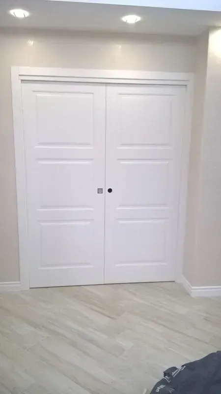 Un paio di porte scorrevoli bianche in una stanza con pavimento in legno.