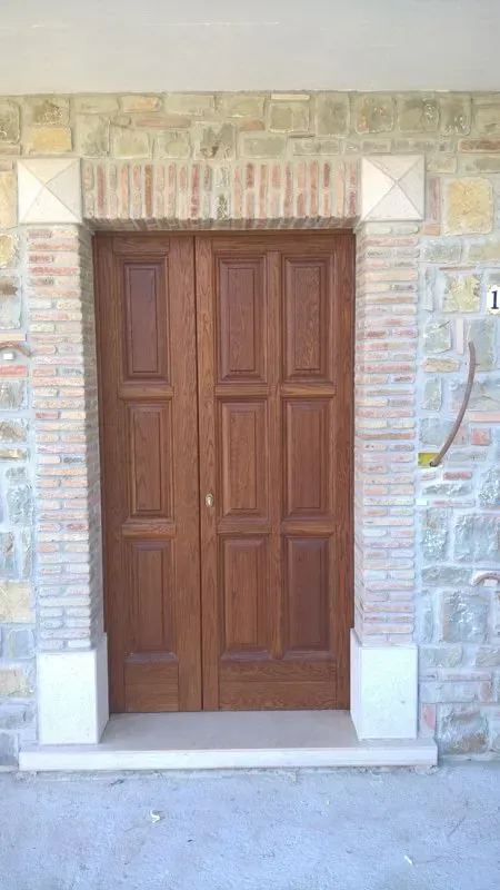 Una porta di legno è posta di fronte a un muro di pietra.