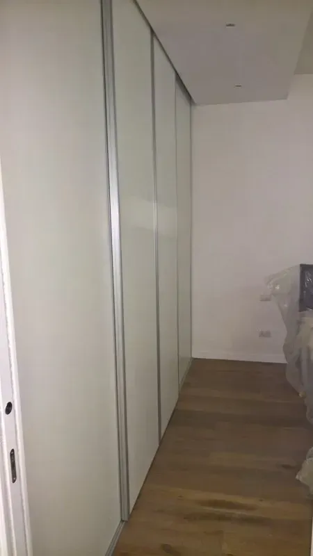 Un corridoio con porte scorrevoli in vetro che conducono a una camera da letto.