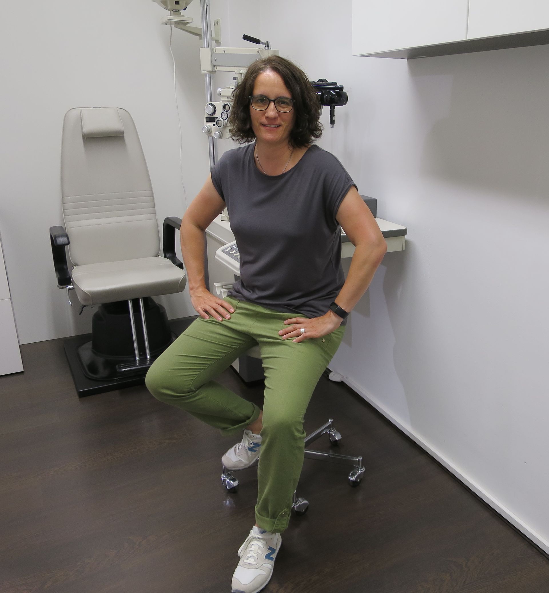 Eine Frau sitzt mit gekreuzten Beinen auf einem Stuhl