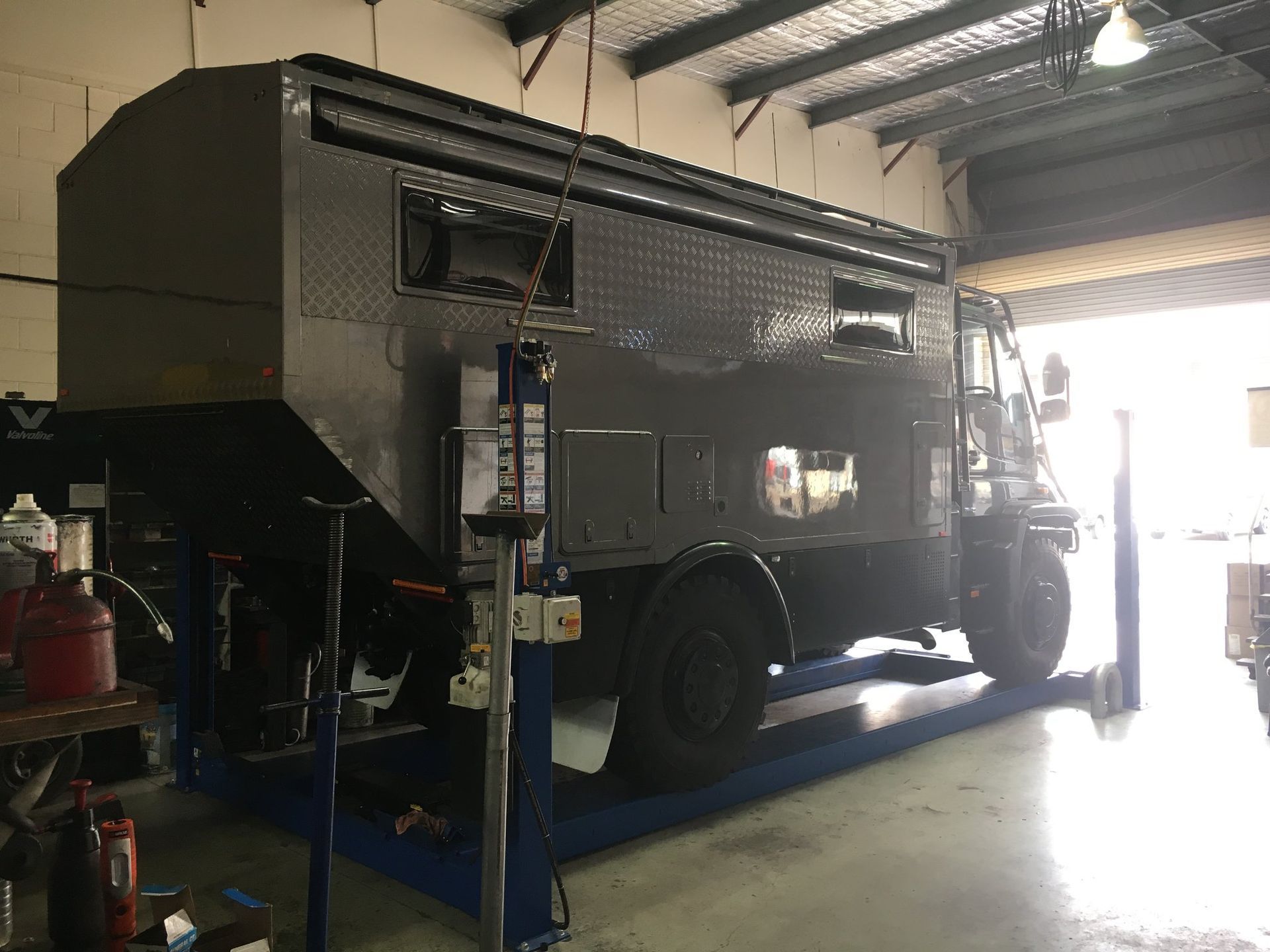 A Large, Gray Camper Vehicle on A Lift Inside a Workshop — Hervey Bay Brake and Exhaust in Pialba, QLD