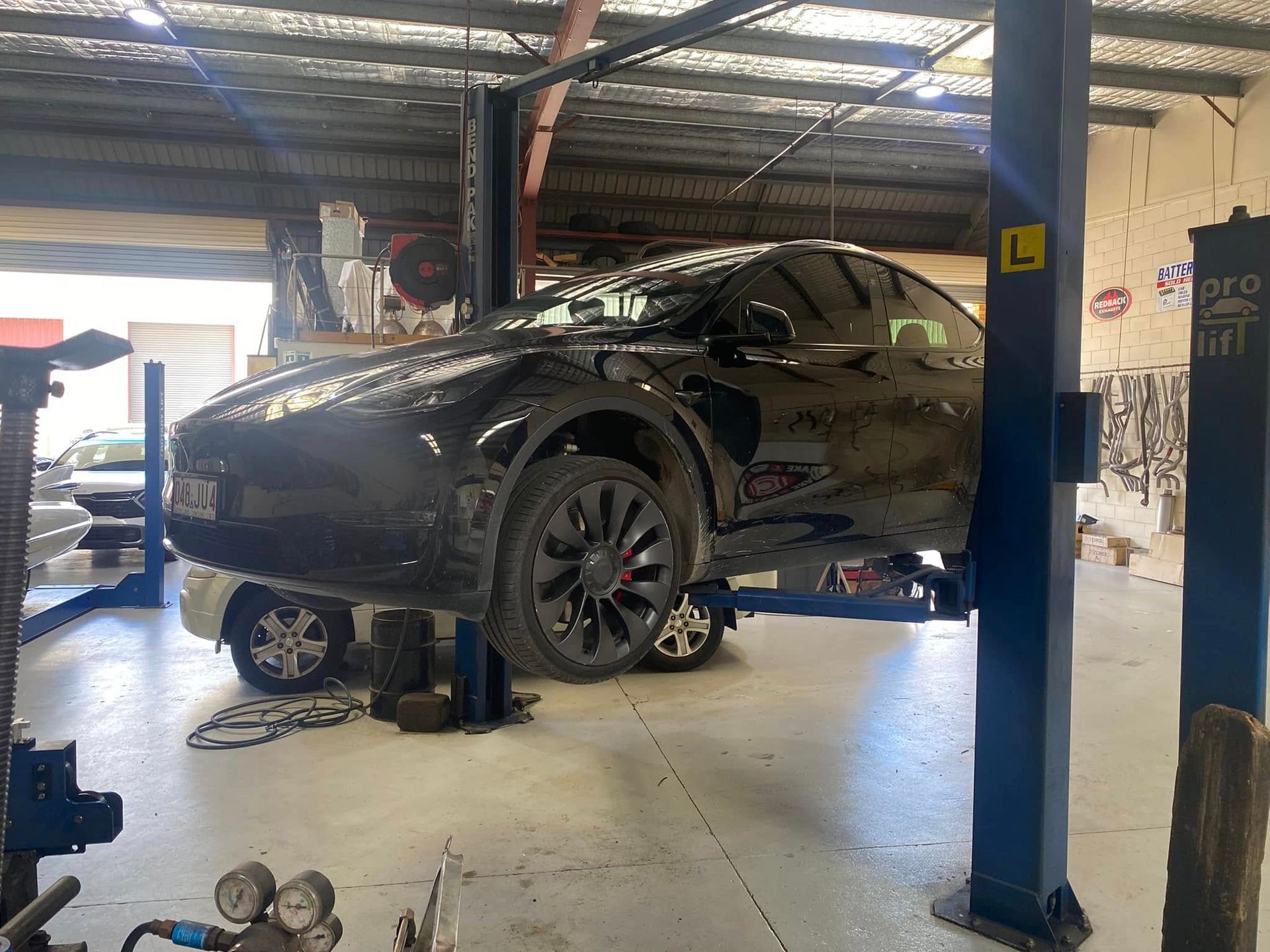 A Black Tesla on A Car Lift in A Garage — Hervey Bay Brake and Exhaust in Pialba, QLD