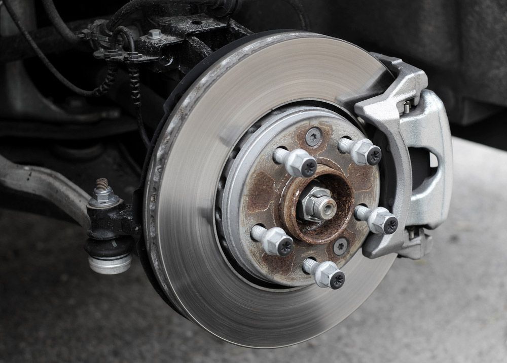 A Car Brake Rotor, Caliper, and Wheel Hub with Lug Nuts — Hervey Bay Brake and Exhaust in Pialba, QLD