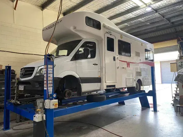 A White Rv on A Blue Lift Inside a Garage — Hervey Bay Brake and Exhaust in Pialba, QLD