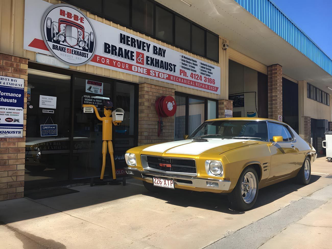 A Yellow Classic Car Parked in Front of A Hervey Bay Brake & Exhaust Shop with A Sign — Hervey Bay Brake and Exhaust in Pialba, QLD