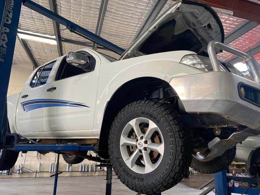 White Pickup Truck Raised on A Lift in A Garage — Hervey Bay Brake and Exhaust in Pialba, QLD