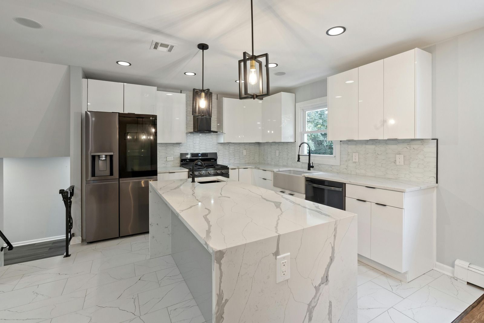 Modern white kitchen with island, stainless steel appliances, and gray countertops.
