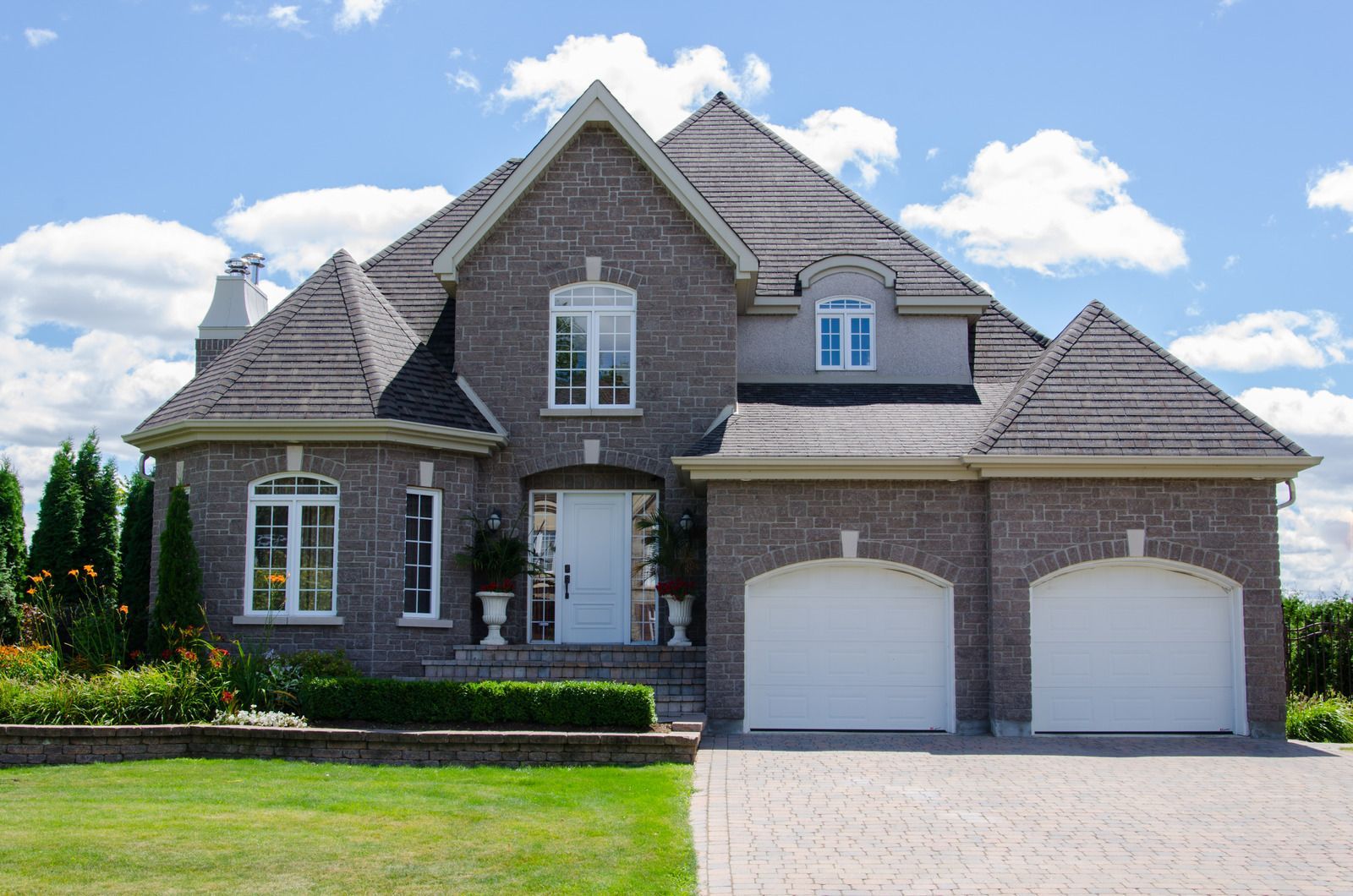 Brick house with two-car garage, white front door, and blue sky.