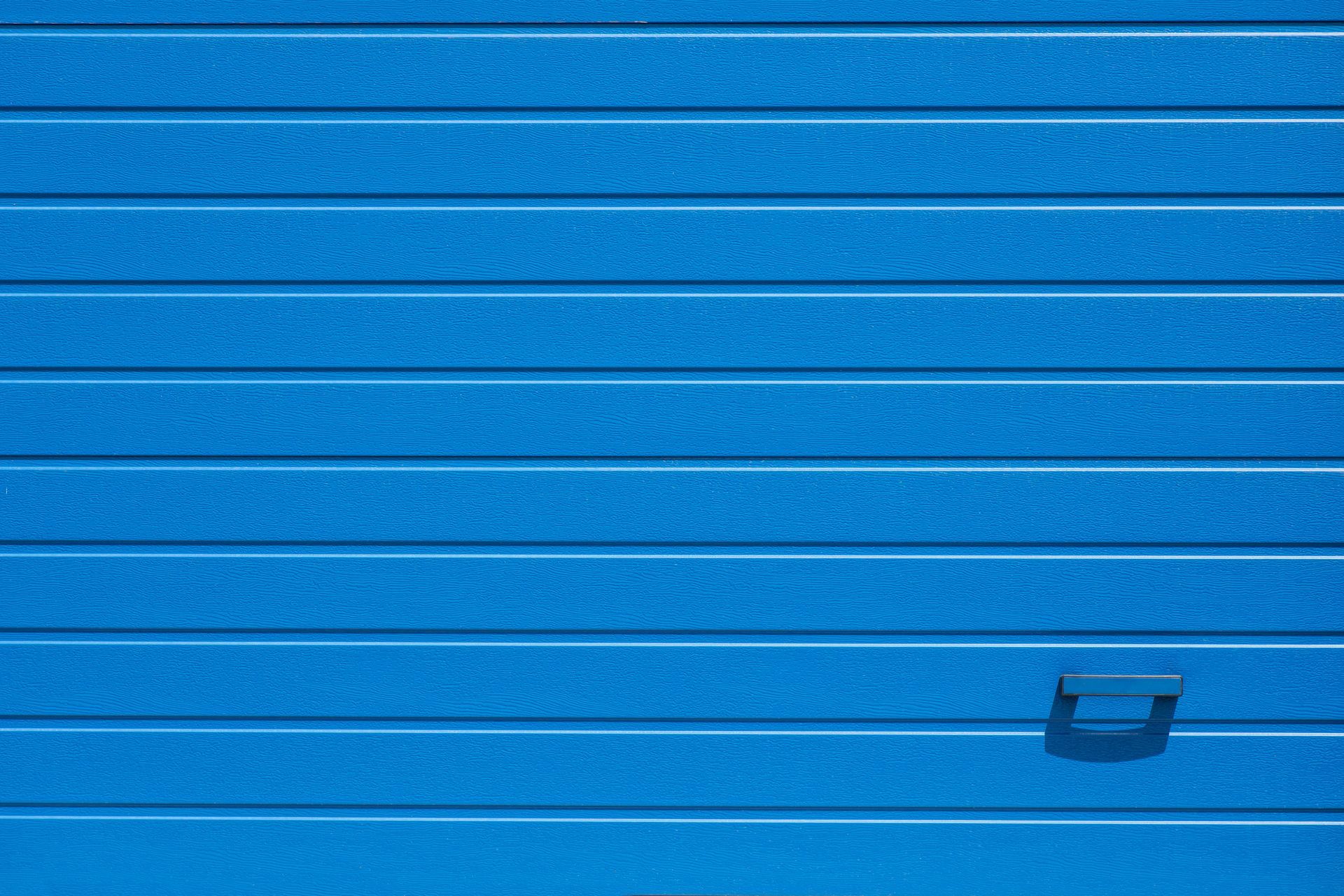 Close-up of a blue garage door with a handle.