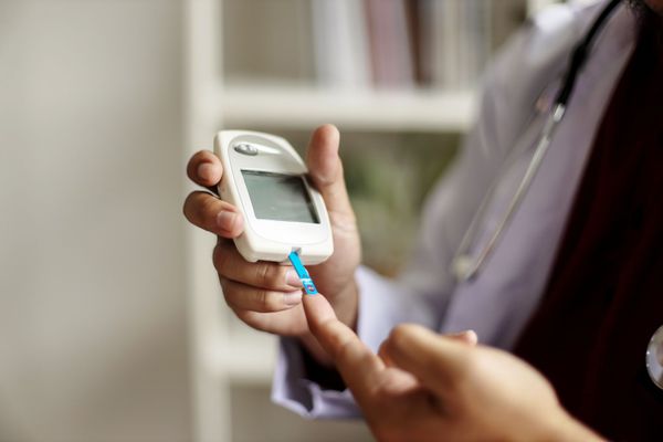 Close-up of a person using a digital glucose monitor for daily remote patient monitoring.
