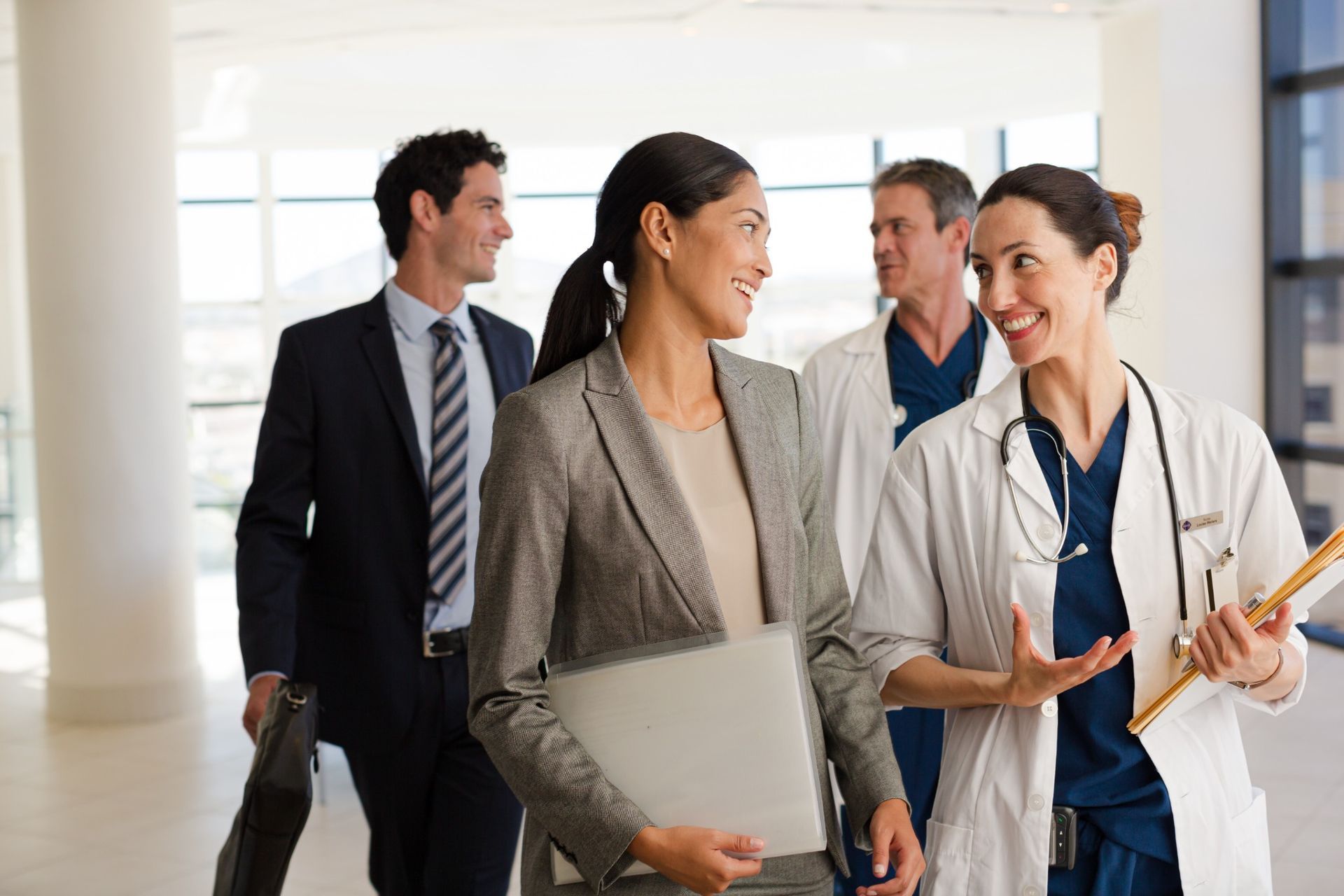 Medical and executive professionals walking and discussing healthcare collaboration in a clinical setting.