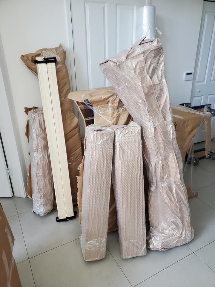 Wrapped furniture pieces ready for moving, stacked against a white door.