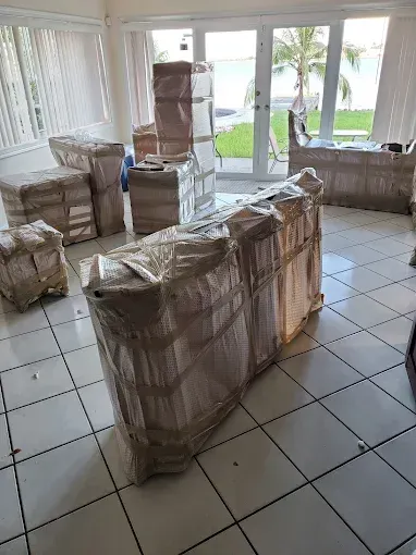 Furniture wrapped in plastic, ready for moving, in a room with a view of the ocean.
