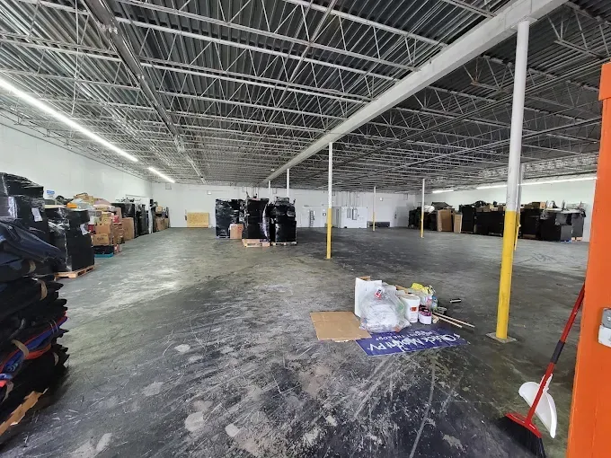 Large warehouse interior with pallets of items and yellow support beams.